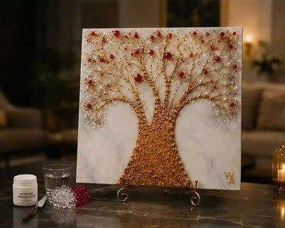 A square wall art piece featuring a stylized tree made of gold-toned branches and red-and-white bead-like accents, displayed on a small stand on a table in a softly lit interior setting.