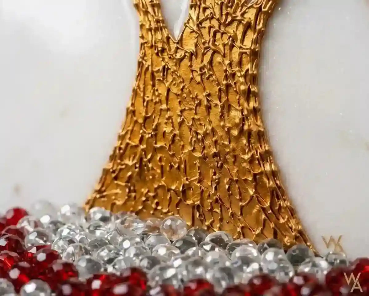 Close-up of a decorative gold tree trunk with a textured, scale-like surface, set against a white background and decorated with red and clear faceted beads at the base.