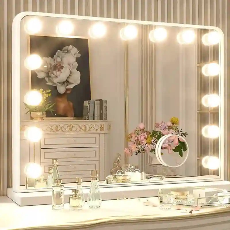 A large rectangular vanity mirror with a white frame and bright round light bulbs around the edges, shown on a dressing table with cosmetics and reflected decor in a softly lit room.