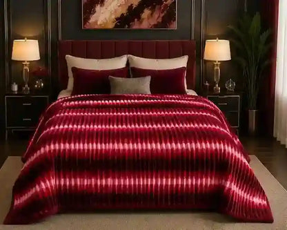 A bed dressed in a plush burgundy and magenta striped comforter set with matching pillows, styled in a dark, elegant bedroom with bedside lamps and a plant.