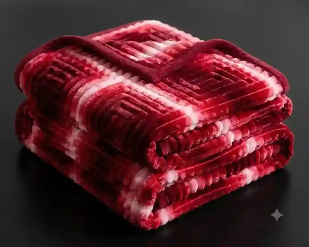 A folded plush throw blanket with a red and white striped pattern, displayed on a dark reflective surface.