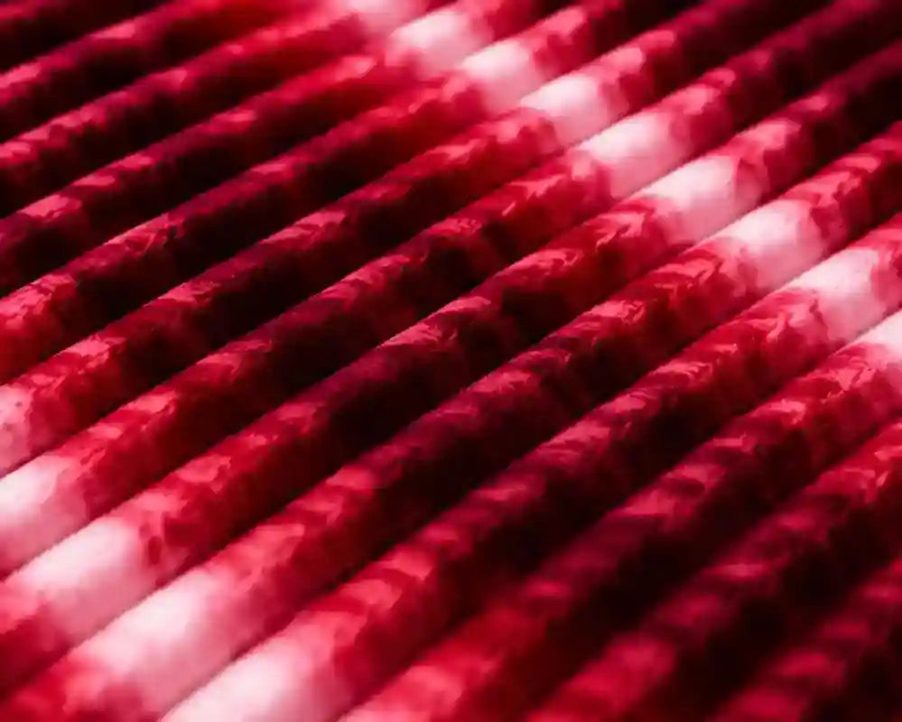 A close-up of multiple red and white marbled or swirled cylindrical rods arranged diagonally, filling the frame.