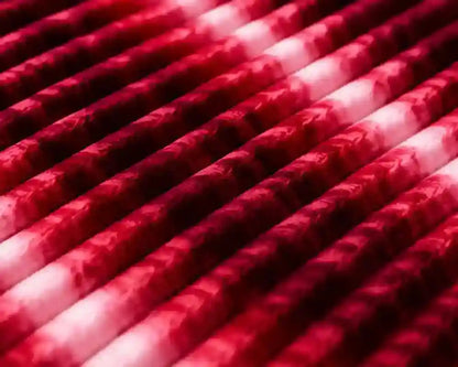 A close-up of multiple red and white marbled or swirled cylindrical rods arranged diagonally, filling the frame.