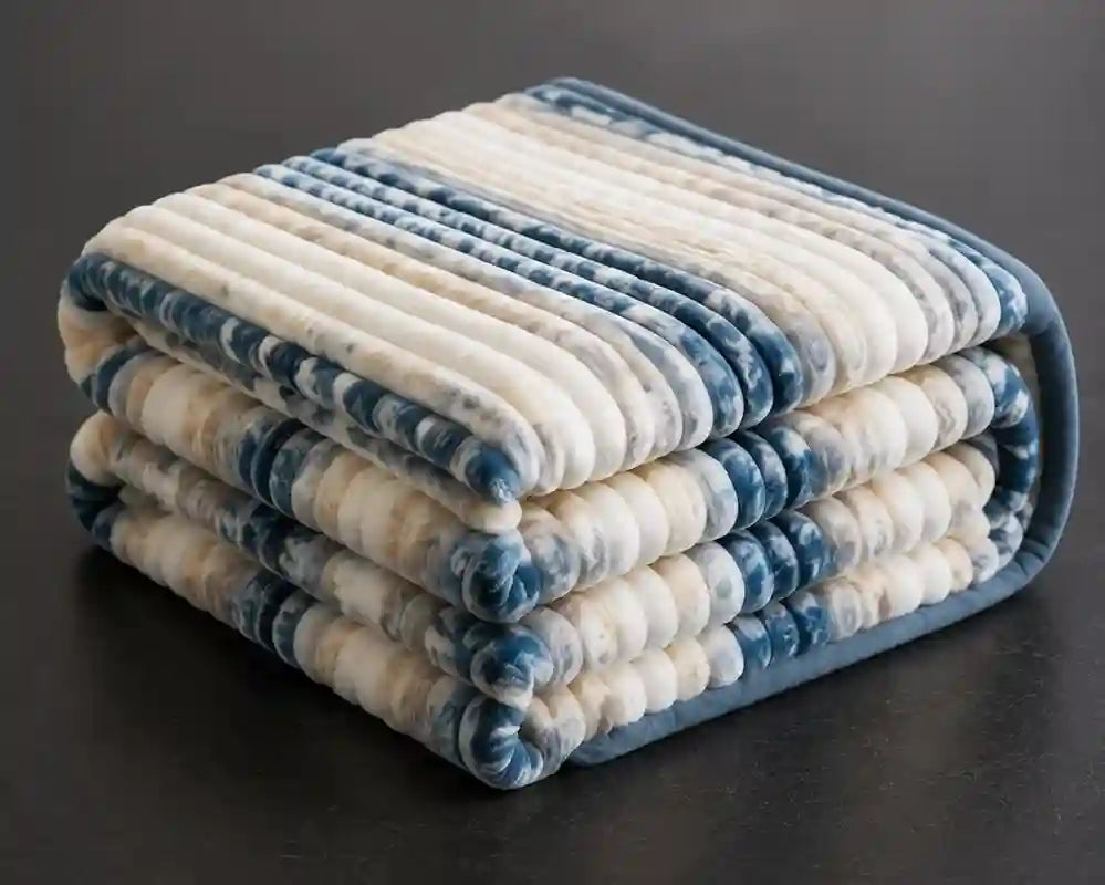 A folded striped quilted blanket with alternating cream and blue marled stripes, displayed on a dark surface.
