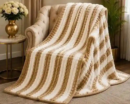 A plush striped throw blanket draped over a tufted armchair in a styled living room setting, featuring alternating cream and tan textured stripes.