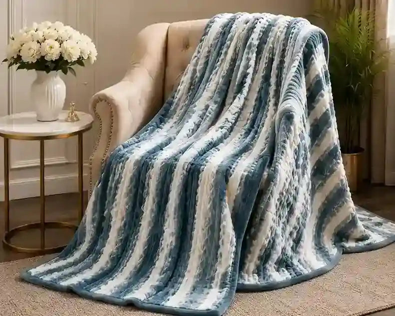 A plush throw blanket with vertical wavy stripes in shades of blue and white, draped over a beige armchair in a styled living room setting.