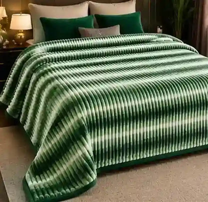 A green striped plush blanket with a ribbed texture draped over a bed in a bedroom setting, styled with green and gray pillows.