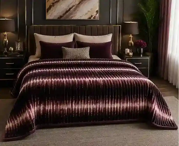 A bed dressed in a plush striped blanket and matching pillows, styled in a dark, elegant bedroom with nightstands, lamps, and wall art.