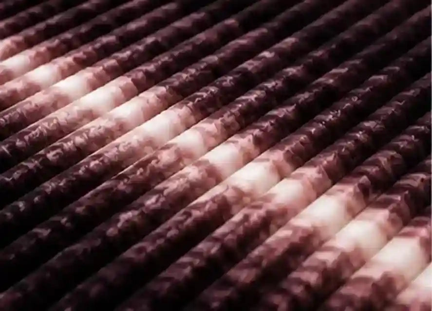 A close-up view of multiple diagonal cylindrical rods with a dark purple and white marbled or mottled pattern, filling the frame.