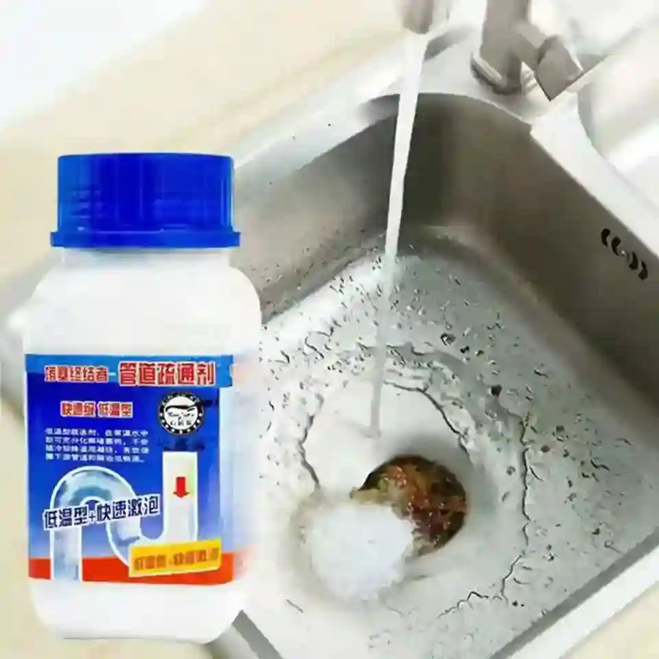 A white plastic bottle of drain cleaner with a blue cap is shown next to a stainless steel kitchen sink with running water and a clogged drain.