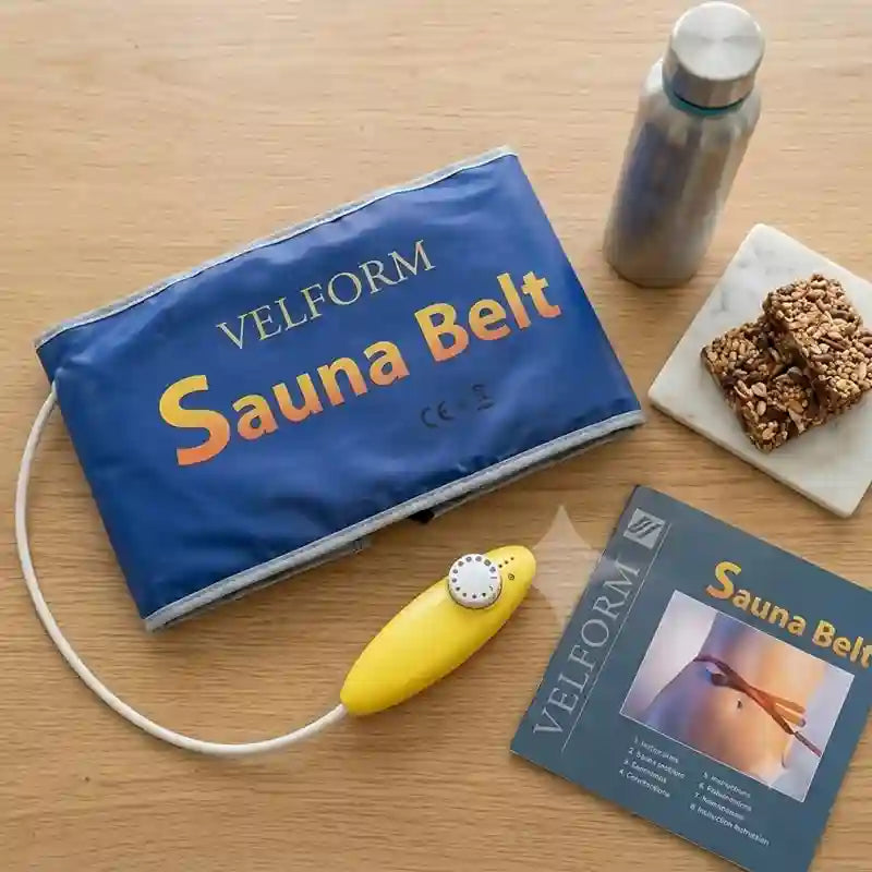 VELFORM Sauna Belt set on a light wood table, including a blue inflatable belt bag, a yellow manual pump, a product booklet, and a stainless steel water bottle. Two granola bars are also placed on a small white dish.