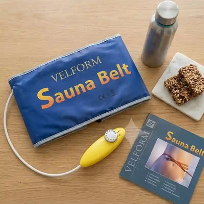 VELFORM Sauna Belt set on a light wood table, including a blue inflatable belt bag, a yellow manual pump, a product booklet, and a stainless steel water bottle. Two granola bars are also placed on a small white dish.