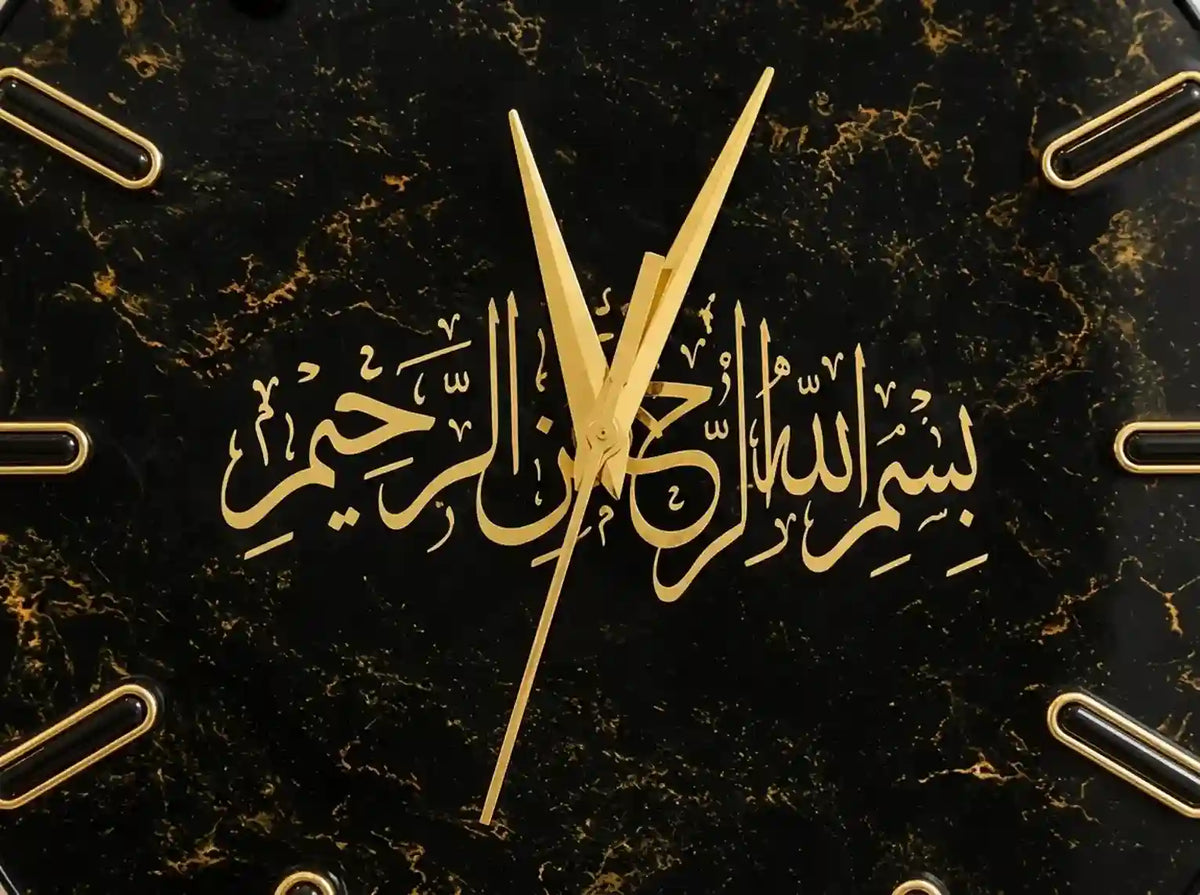 A close-up of a black marble clock face with gold Arabic calligraphy and gold hands, showing the center of the time between 11 and 1.