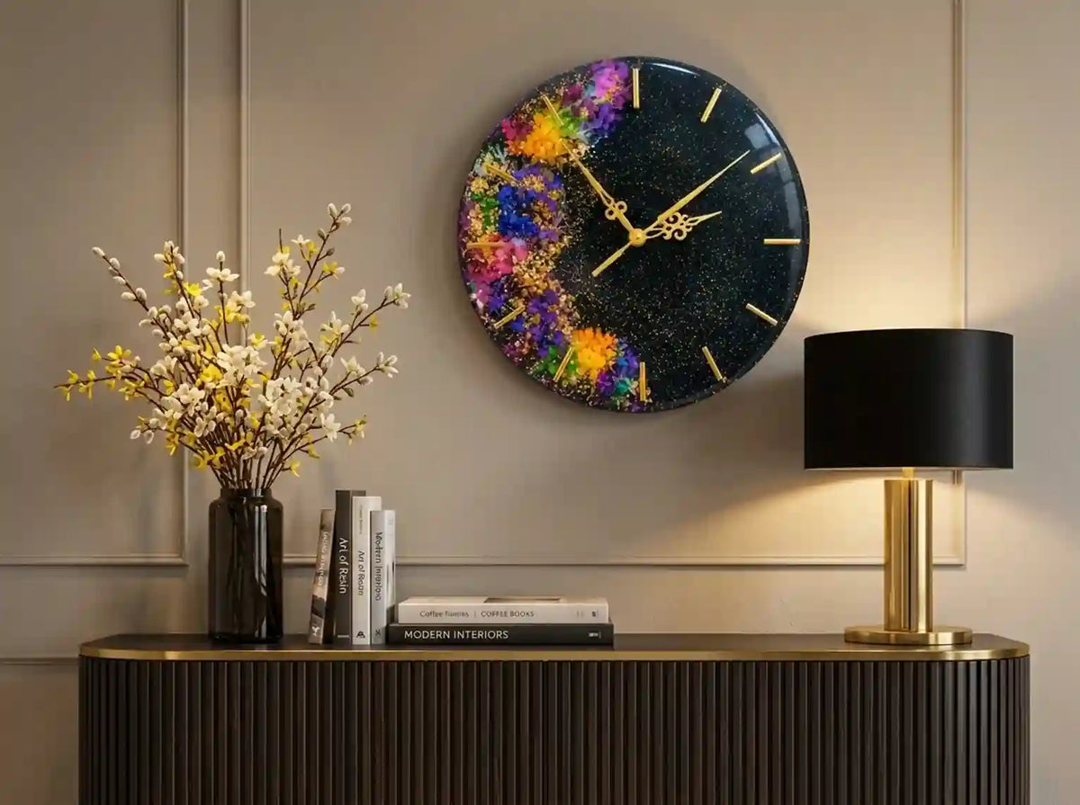 A round wall clock with a colorful cosmic paint-splatter design on a black glittery background, styled in a modern living room setting above a console table.