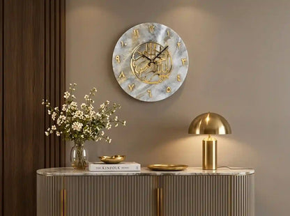 A round wall clock with a white marble pattern face and gold Arabic numerals, styled in a modern home interior above a console table with a gold lamp and flowers.
