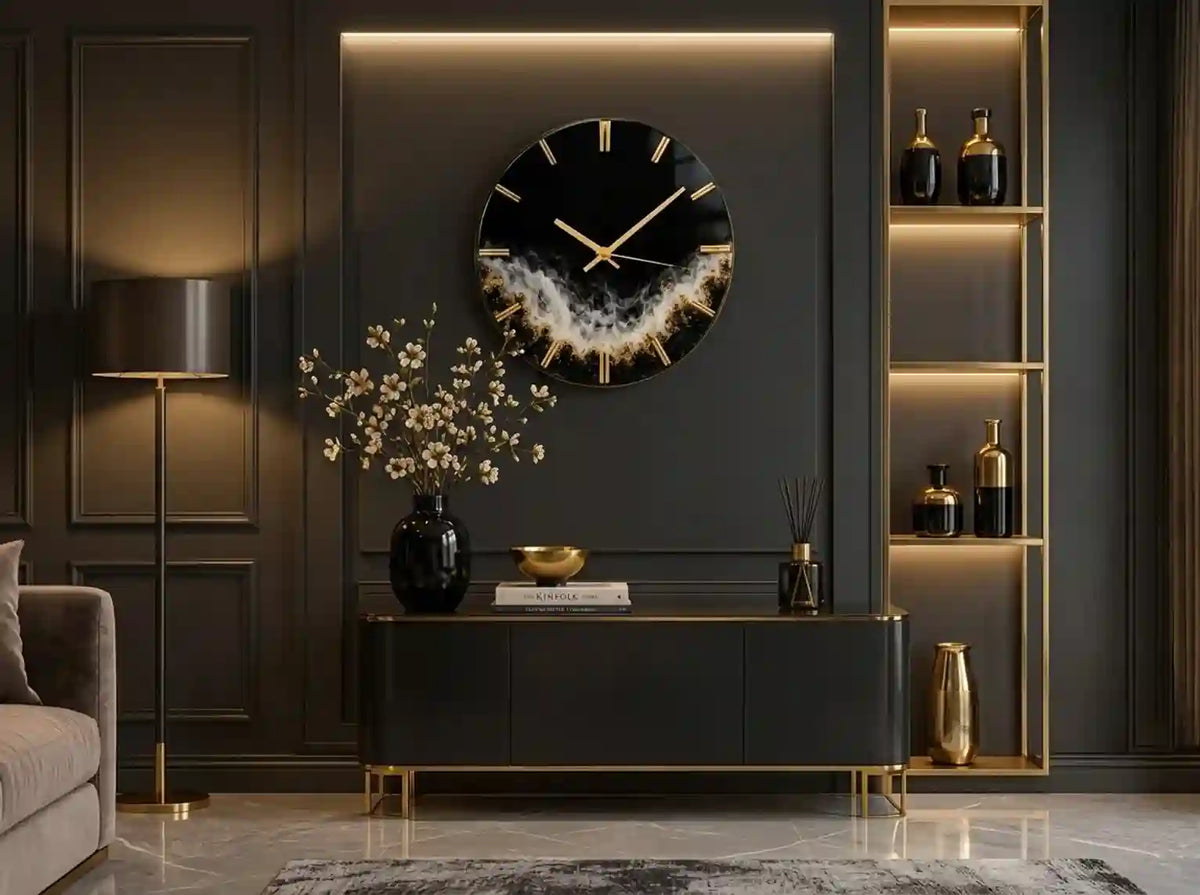 A modern round wall clock with a black face, gold hour markers and hands, and a textured gold and white geode-like center, mounted on a dark gray paneled wall above a console table in a styled living room.