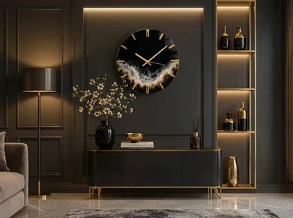 A modern round wall clock with a black face, gold hour markers and hands, and a textured gold and white geode-like center, mounted on a dark gray paneled wall above a console table in a styled living room.